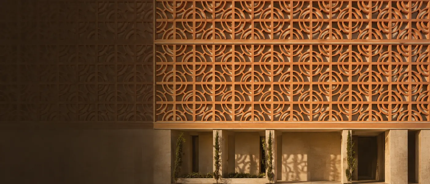 Terracotta screen wall on a hotel facade, raking afternoon light